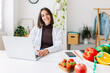 © Xavier Lorenzo - Smiling dietitian woman looking at camera sitting at hospital workplace. Nutrition, diet and professional healthcare worker concept