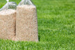 Bags of lawn fertilizer and herbicide in yard with healthy grass. Lawn care, weed control and landscaping concept.