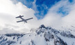 Airplane flying over Canadian Mountain Landscape covered in snow. Aerial Background in BC, Canada