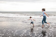 © moonmovie - Mom and son Toddler are running along the black sand beach along the ocean and laughing happily. They play in the water and spend time together. Family summer vacation. Mothers Day.