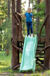 Little boy on top wooden playground made of eco materials - wooden tree trunk logs construction