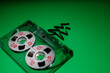 Green background, with transparent plastic audio cassette with red prints of Christmas toys on white discs. and Christmas tree from tape. Christmas and music theme. Free space for text