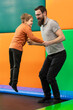 Smiling father and young son holding hands and jumping on trampoline.