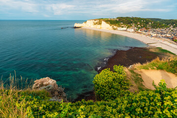Wall Mural - Panoramic view of pebble beach with white chalk cliffs and natural arches in Etretat town and beautiful famous coastline during low tide, Normandy, France. French sea coast in Normandie