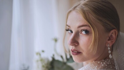 The bride with a bouquet at the window.