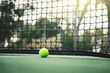 Tennis ball on tennis court with net in background