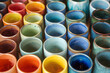 Colorful ceramic cups neatly lined up.  Each cup boasts its own distinct shape and design, some sleek and modern with clean lines, others more whimsical with playful curves and intricate patterns