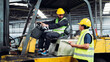 © NewSaetiew - Two men in yellow and green safety vests are standing next to a forklift