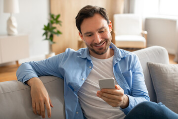 Poster - Man Sitting on Couch Looking at Cell Phone