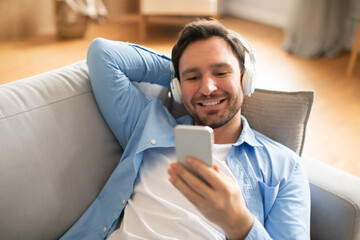 Poster - Man Reclining on Couch Using Cell Phone