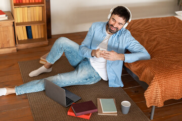 Poster - Man Sitting on Floor With Laptop, Using Phone