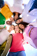 © CarlosBarquero - Vertical Low angle of a group of multiracial young only women looking at camera standing in a circle smiling and hugging each other. Female people embracing together having fun and enjoying friendship