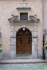 Wall Mural - Wooden antique brown door with sculpture ornamental frame on orange wall, Stockholm Sweden. Vertical