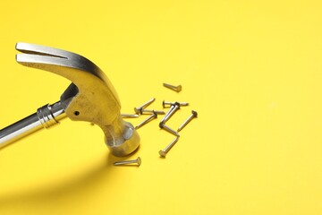 Poster - Hammer and metal nails on yellow background, closeup. Space for text