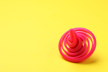 One pink spinning top on yellow background, closeup. Space for text