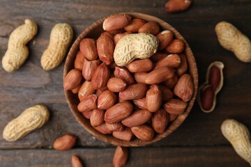 Wall Mural - Fresh peanuts in bowl on wooden table, flat lay