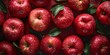 A close-up view of fresh, dewy red apples densely packed, featuring a few leaves, exhibiting a vibrant and appetizing appearance.