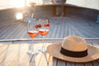 Wine on a yacht in sea. Romantic picnic in summer travel at sunset. Two wineglasses with cherry, straw hat on beautiful wooden deck. Alcohol-free drink on vacation. Enjoyment, relaxation on holidays