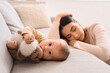 Little baby with toy on sofa and young woman suffering from postnatal depression at home, closeup