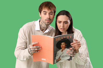 Canvas Print - Young couple reading magazine on green background