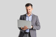 © Pixel-Shot - Handsome businessman using laptop on light background