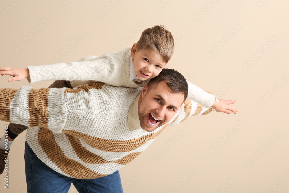 Happy father and his little son having fun together on beige background