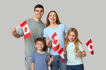 Wall Mural - Happy family with flags of Canada on grey background