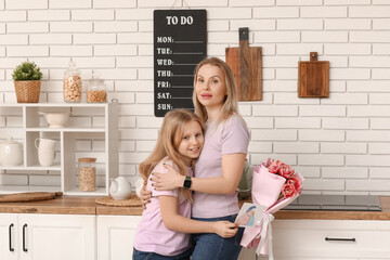 Wall Mural - Cute little girl with her mom, drawing and bouquet for Mother's Day hugging at home