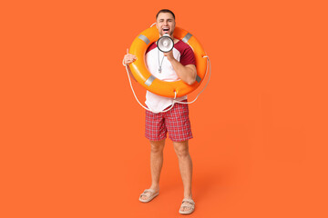 Wall Mural - Happy young lifeguard with lifebuoy and megaphone on orange background