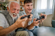 teenager male and his grandfather senior man play console video game