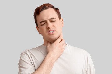 Poster - Young man with sore throat on light background