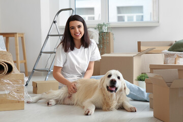 Wall Mural - Young happy woman and cute Labrador dog with boxes on moving day at home