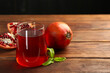 Tasty pomegranate juice in glass and fresh fruits on wooden table, closeup. Space for text