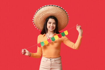 Sticker - Beautiful young happy woman in sombrero with garland on red background. Cinco de Mayo celebration