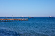 Pier in the sea with ships in the distance on the horizon. Blue sky over blue sea 