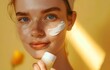 Young beautiful model girl applying sunscreen creme on facial skin. Natural Beauty. Cosmetics for summer with SPF protection. Yellow cosmetic product.