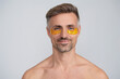 Eye patch. Beauty man face with under eye collagen pads. Mature man has fresh healthy skin with collagen patches under eyes. Hydrate and nourish the skin. Man applying eye patches. Spa care