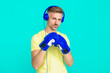 Mature man boxer in headphones. Sport man boxing. Strong man listen music. Sportsman in gym. Boxer in sportswear. Exercising and punching. Sportsman in boxing gloves isolated on blue. Achievement