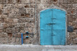 A old stone wall with a azure painted metal door 