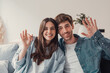 Head shot positive loving bonding married couple sitting on comfortable sofa, looking at camera, holding video call with friends. Happy family bloggers recording video for personal channel at home..