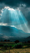 Sunbeams piercing through stormy sky over hills - Dramatic view of sunbeams bursting through a dark, stormy sky over a hilly landscape, evoking hope