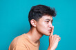 © Gatot - Side view of young Asian man keeps finger on lips, asks not tell secret information or keep silence