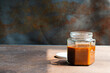 Homemade caramel sauce in a glass jar on rustic table