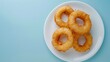 Flat lay fried onion ring salty snack crunchy on white plate copy space isolated