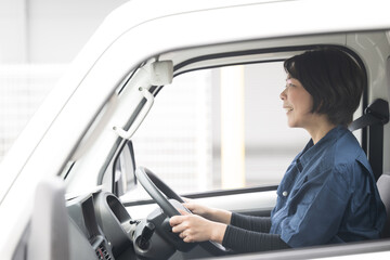 Profile of a middle-aged woman in work clothes driving a truck Image of the transportation and delivery industry, etc.