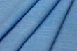Texture background made of blue fabric in the form of diagonal folds. Textiles for sewing clothes close-up.