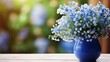 Blue flowers of a forget-me-not in a blue vase on a table. Blurred background