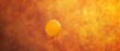 The tranquil beauty of a solitary yellow balloon suspended in mid-r agnst a backdrop of intense orange, evoking a sense of peaceful solitude.