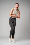Fototapeta  - Girl in Beige Tank Top and Grey Jeans on gray background