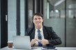 © SOMKID - Professional business man trader using laptop computer sitting at office desk in modern office.